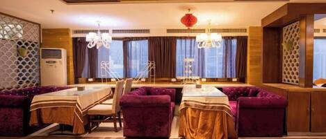 A dining area with purple upholstered seating, a checkered floor, and a chandelier.