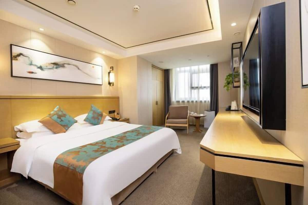 Habitación de hotel con una cama grande, un escritorio, un televisor de pantalla plana y un cuadro en la pared.