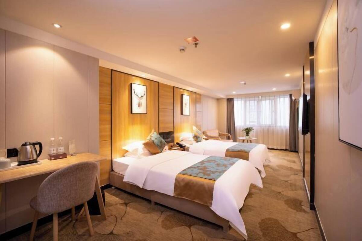 Una habitación de hotel con dos camas, un escritorio, una silla y un televisor.