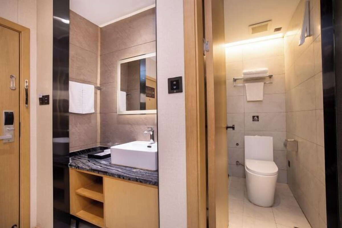 Un baño moderno con lavamanos de encimera de mármol, un espejo y un inodoro.