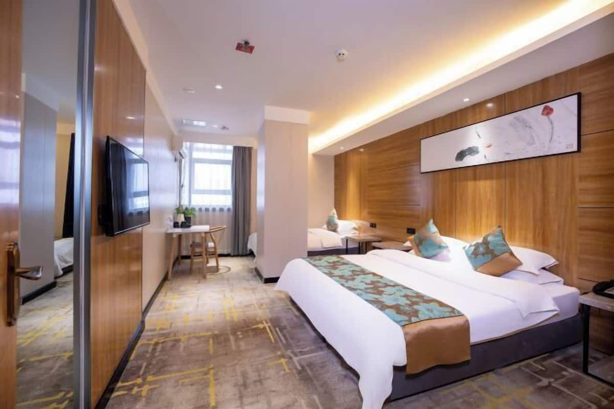 Habitación de hotel con una cama grande, un escritorio, una silla y un televisor.