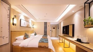 Une chambre d’hôtel équipée d’un lit, d’une table de chevet, d’une télévision et d’œuvres d’art accrochées aux murs.