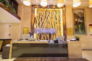 Balcão de recepção de hotel com design moderno, tela digital e parede decorativa.