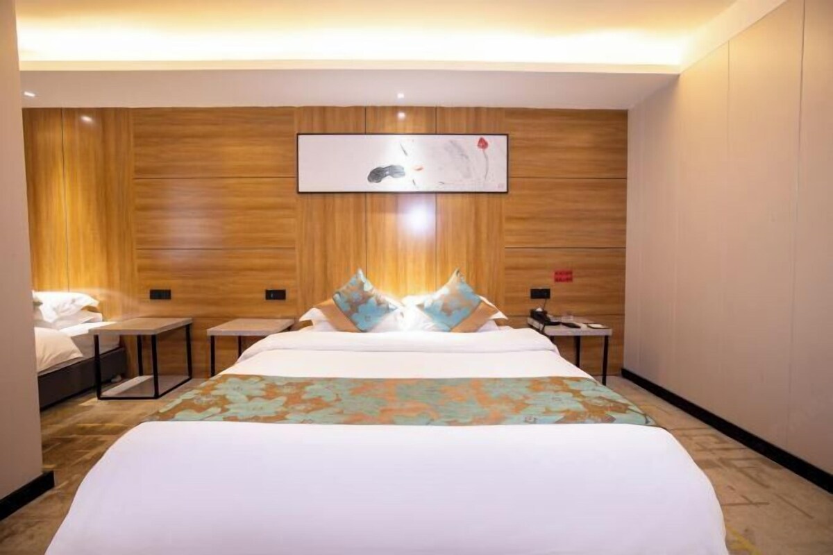 Habitación de hotel con una cama grande, dos mesitas de noche, un televisor de pared y un panel de pared de madera.