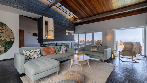 A modern living room with a large gray sofa, a round coffee table, and a wooden bench.