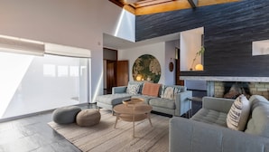 A modern living room with a large window, a fireplace, and a round coffee table.