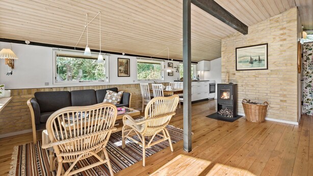 A cozy living room with a wooden ceiling, a fireplace, and a dining area with wicker chairs. - 4 bedroom cozy home in Jægerspris (Jægerspris)