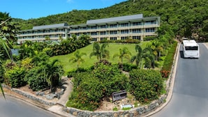 A modern hotel with a multi-story structure, a well-maintained lawn, and a bus on the road.
