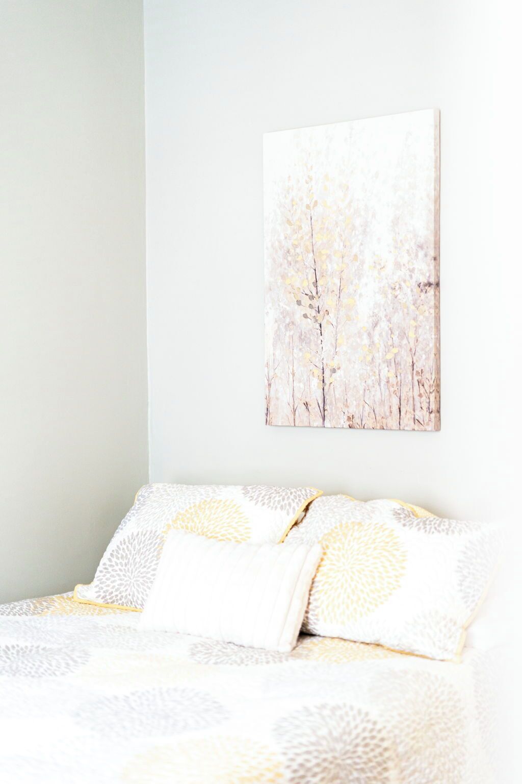 Un dormitorio con cama, almohadas y un cuadro colgado en la pared.