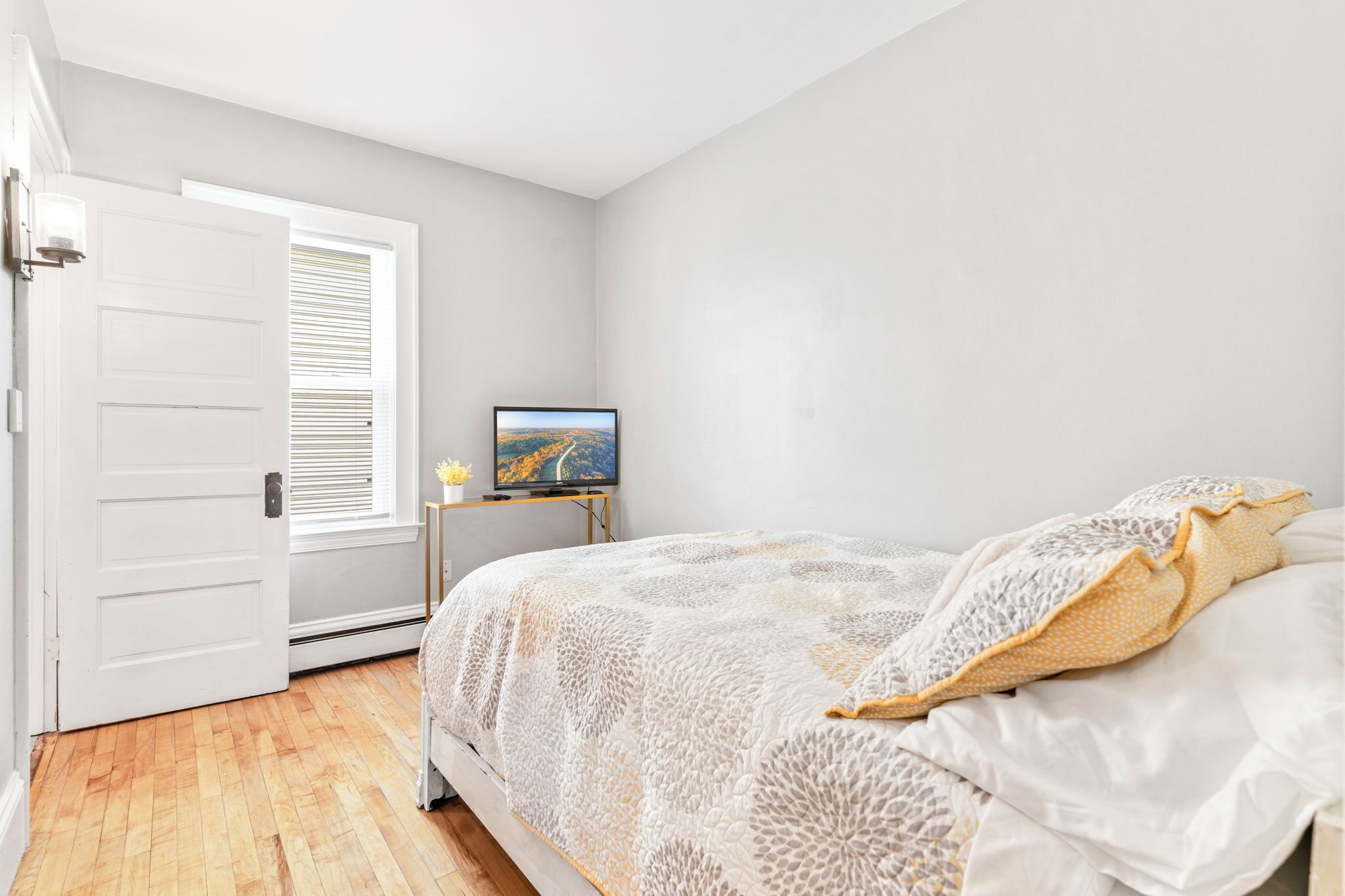 Un dormitorio con cama, televisor y puerta.