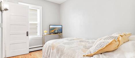 Un dormitorio con cama, televisor y puerta.