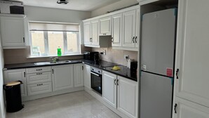 A kitchen with white cabinets, a stainless steel refrigerator, and a window with a view of the outside. - 4-bedroom house in charming Lucan with WiFi (Lucan)