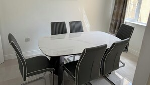 A dining area with a marble table and black upholstered chairs, a framed picture on the wall, and a window with curtains. - 4-bedroom house in charming Lucan with WiFi (Lucan)