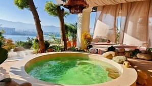 Un jacuzzi con vistas a un cuerpo de agua y montañas al fondo.