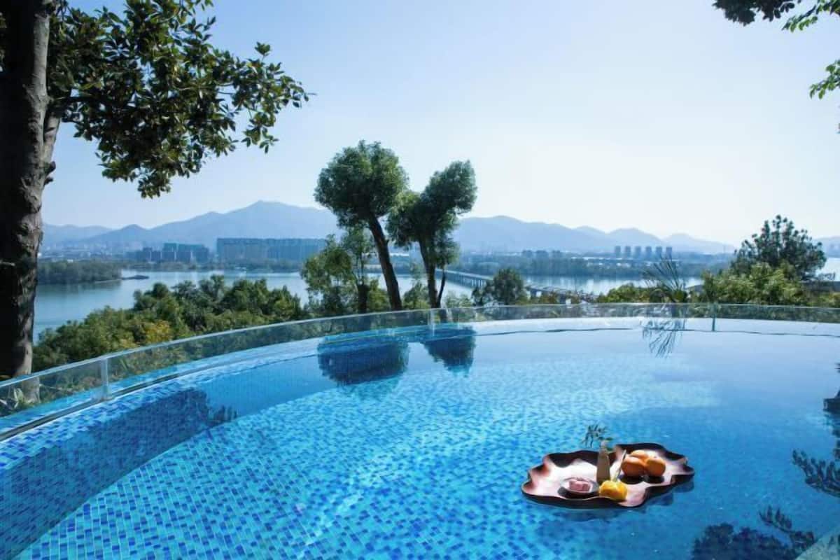 Una piscina infinita con vistas despejadas a montañas y un paisaje urbano al fondo.