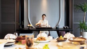 Un espace repas où un chef prépare les plats, une table dressée avec différents mets et une plante en pot.