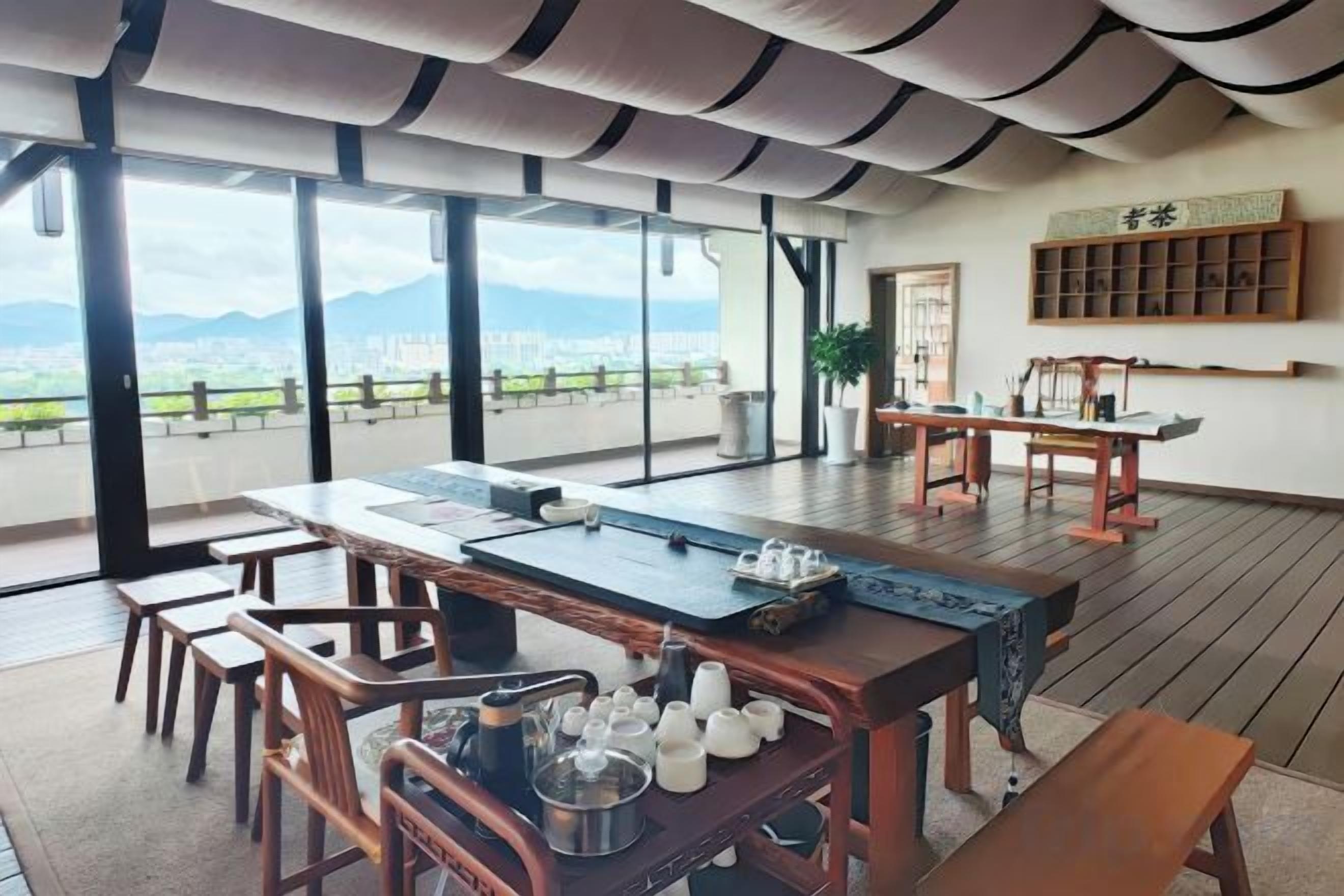 A spacious room with a large dining table, chairs, and a view of the city and mountains.