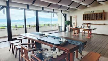 A spacious room with a large dining table, chairs, and a view of the city and mountains.