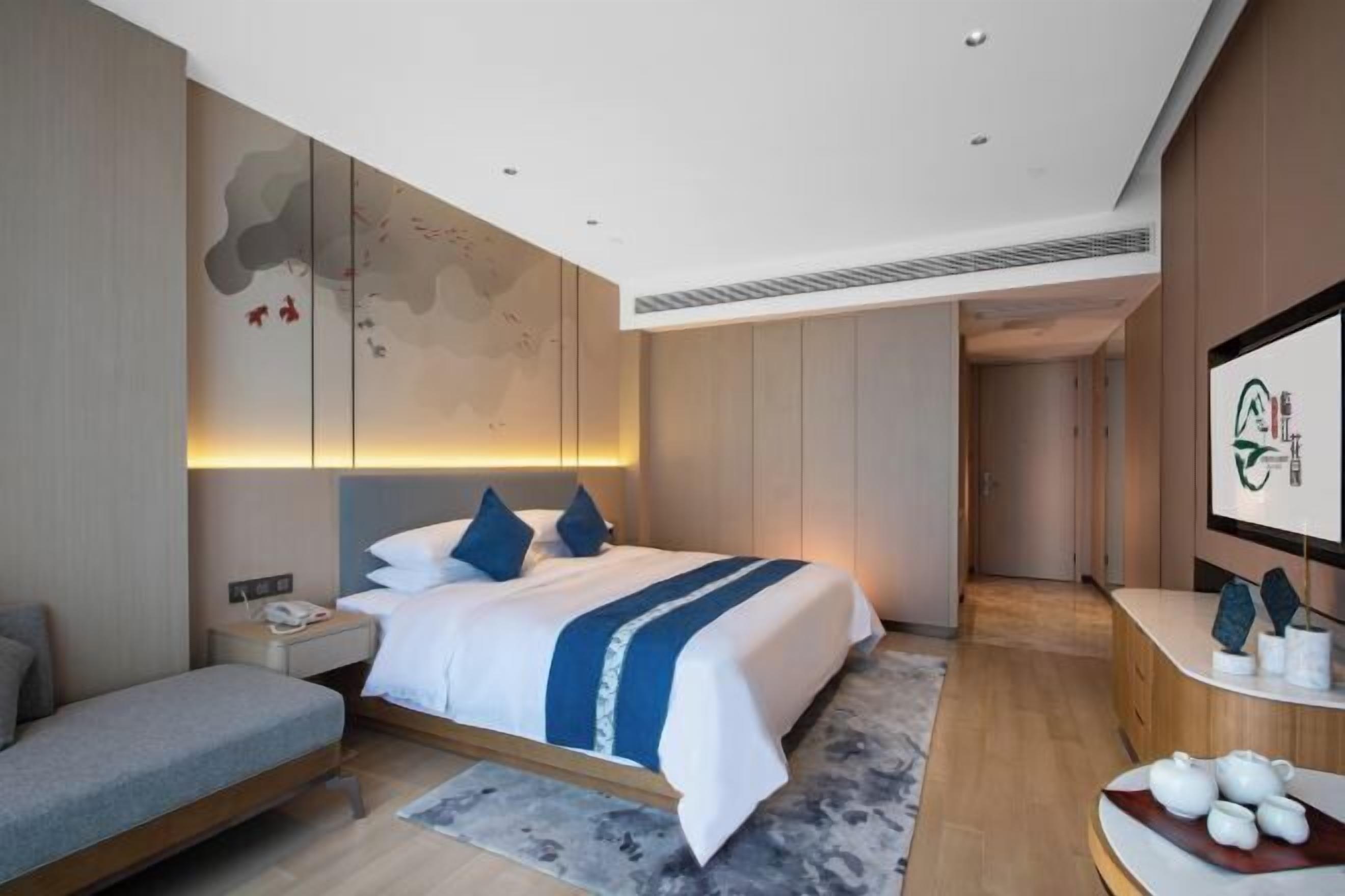 Een moderne hotelkamer met een bed, nachtkastje en een bureau.