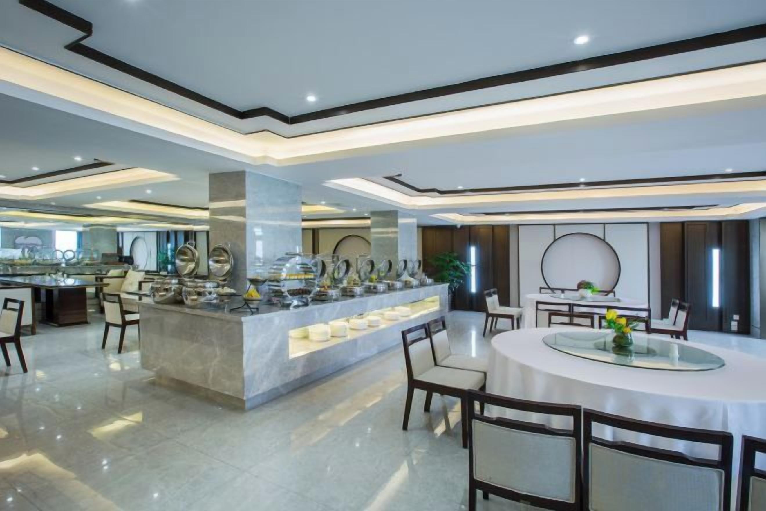 Un espace repas moderne dans un hôtel, avec un buffet, une table ronde entourée de chaises et un bar.