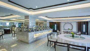 Un espace repas moderne dans un hôtel, avec un buffet, une table ronde entourée de chaises et un bar.