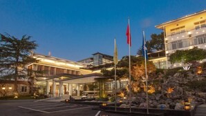 Un hôtel moderne doté d’une façade en verre, d’une entrée aménagée et de plusieurs drapeaux.