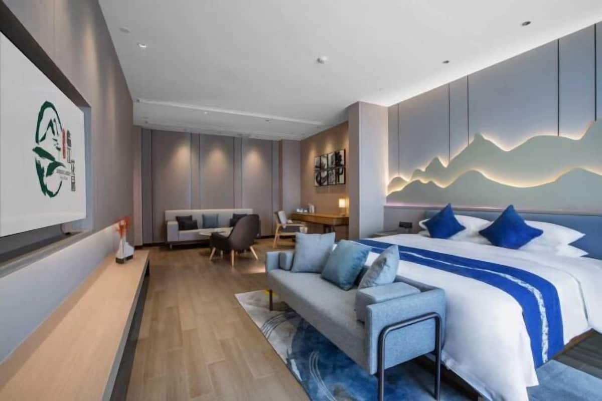 Una habitación de hotel moderna con cama, sofá y una zona de escritorio.