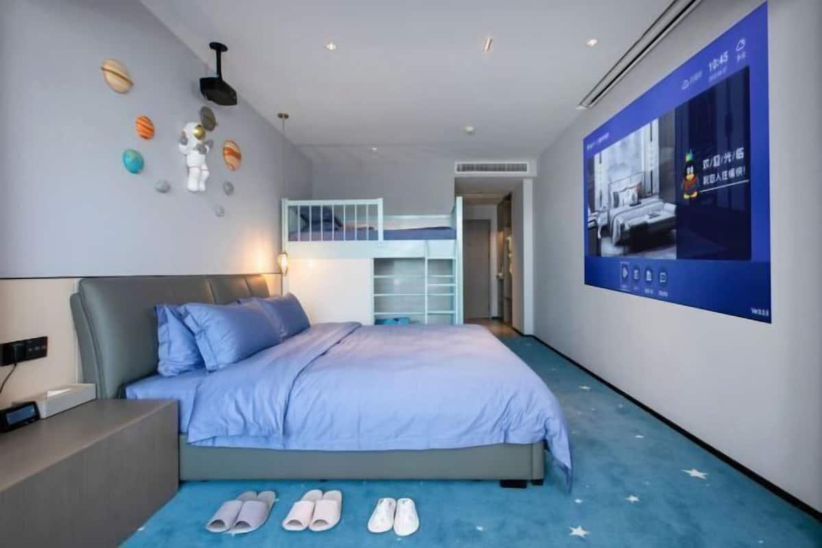 Un dormitorio moderno con una litera, un televisor en la pared y una lámpara en el techo.
