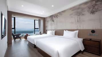 Een moderne hotelkamer met twee bedden, een groot raam en uitzicht op de bergen.