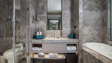 A modern bathroom with a glass shower enclosure, a marble sink, and a freestanding bathtub.
