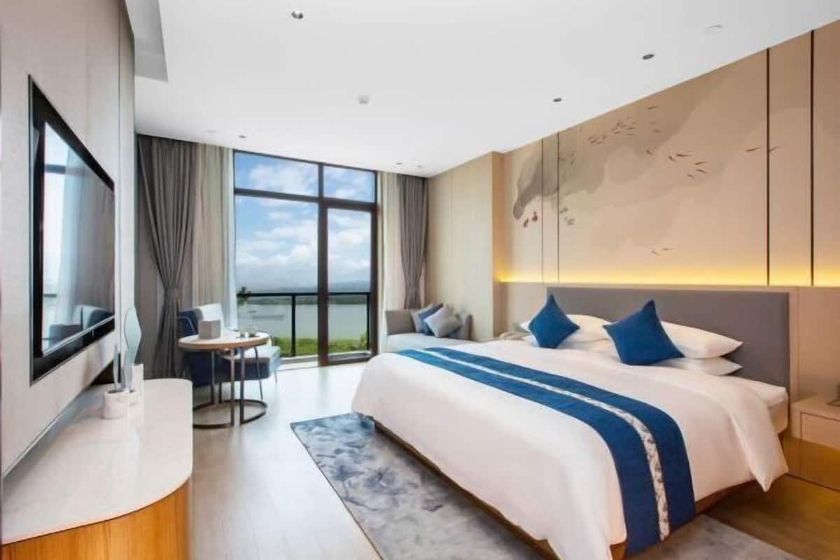 Habitación de hotel moderna con una cama grande, un escritorio y vistas al exterior.