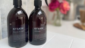 Two dark-colored bottles of KIT&KIN liquid detergent on a white surface.