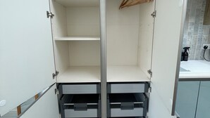 A walk-in closet with open shelves and drawers, a hanging rod, and a tiled floor.