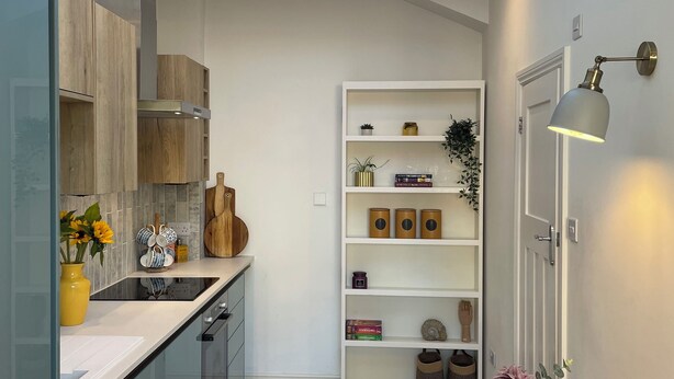 A modern kitchen with a skylight, a wooden dining table, and a white shelving unit.