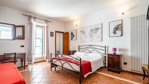 A bedroom with a bed, a desk, a chair, a dresser, and a window with curtains. - Ostuni's Corner by Rentbeat (Ostuni)