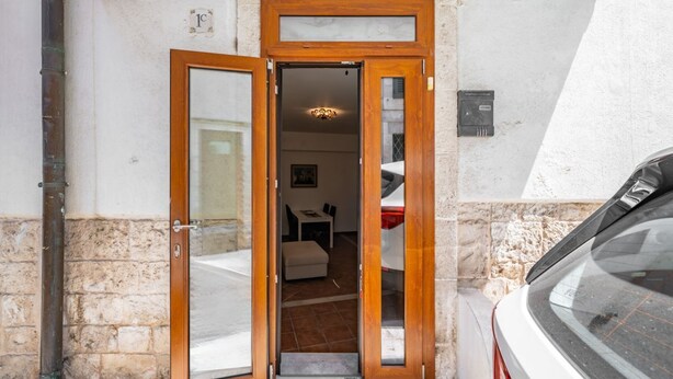 A wooden-framed door leading into a room with a tiled floor and a small table. - Ostuni's Corner by Rentbeat (Ostuni)