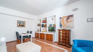 A living room with a sofa, a dining table with chairs, a TV, and a cabinet. - Ostuni's Corner by Rentbeat (Ostuni)