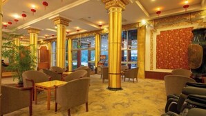 A hotel lobby with golden columns, comfortable seating, and a red patterned wall. - Hengdian World Studios Resort (Dongyang)