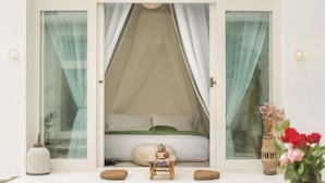 Ein Schlafzimmer mit Baldachinbett, einem kleinen Tisch mit Lampe und einer Vase mit Blumen.