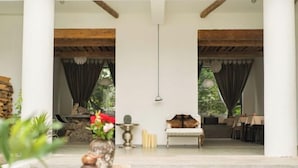 Ein großzügiger Innenbereich mit hoher Decke, Holzbalken und einer Sitzecke mit Sofa und Sesseln.