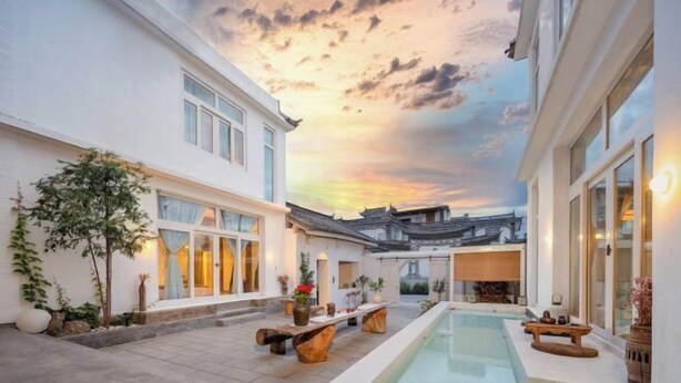 Ein modernes Gebäude mit Pool, traditioneller Architektur und einem Sonnenuntergangshimmel.