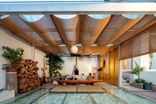 Un interior moderno con piscina de vidrio, techo de madera y varias plantas.