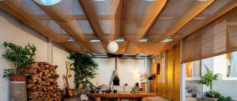 Un interior moderno con piscina de vidrio, techo de madera y varias plantas.