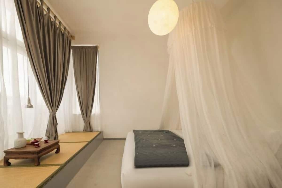 Ein schlicht eingerichtetes Zimmer mit einem Bett, einem kleinen Tisch und einer Pendelleuchte.