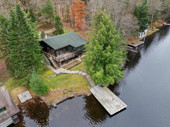 A cabin with a dock extending into a lake, surrounded by trees.