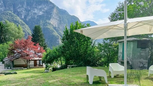 Ein Garten mit weißem Sonnenschirm, weißen Stühlen und einer Steinstruktur.