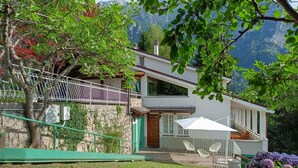 Ein zweistöckiges Haus mit Steinverkleidung, einem Balkon und Blick auf die Berge.