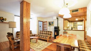 Ein gemütliches Wohnzimmer mit Holzboden, einem Karomuster-Sofa, einem Esstisch und einem Kamin.