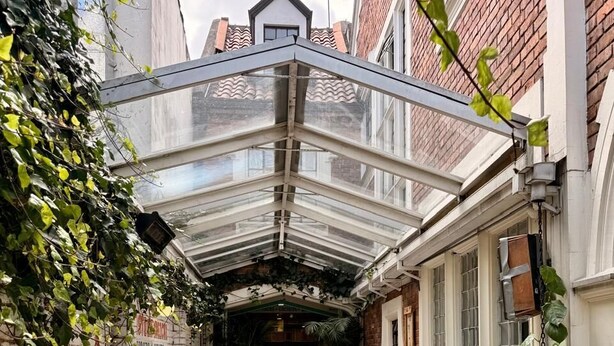Un espace extérieur abrité, aménagé avec des tables et des chaises, des murs en briques et un sol carrelé.