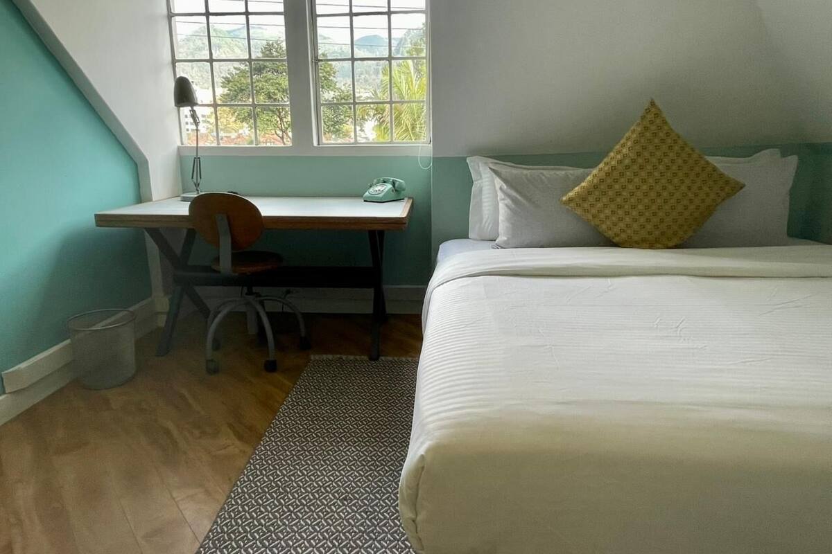A bedroom with a bed, a desk, and a chair.